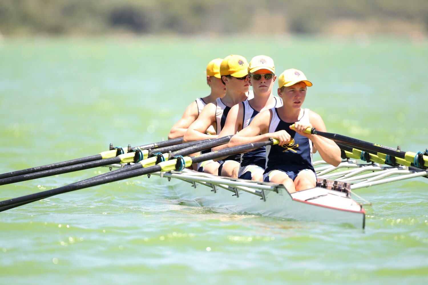 four people with yellow caps on in a rowing boat