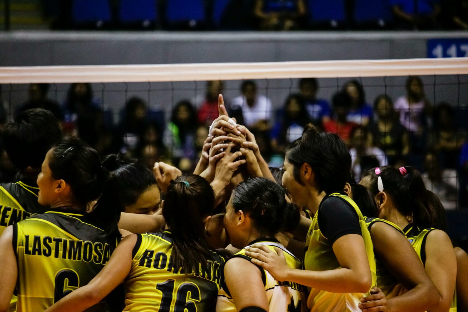 a vollyball team group huddle with there arms together